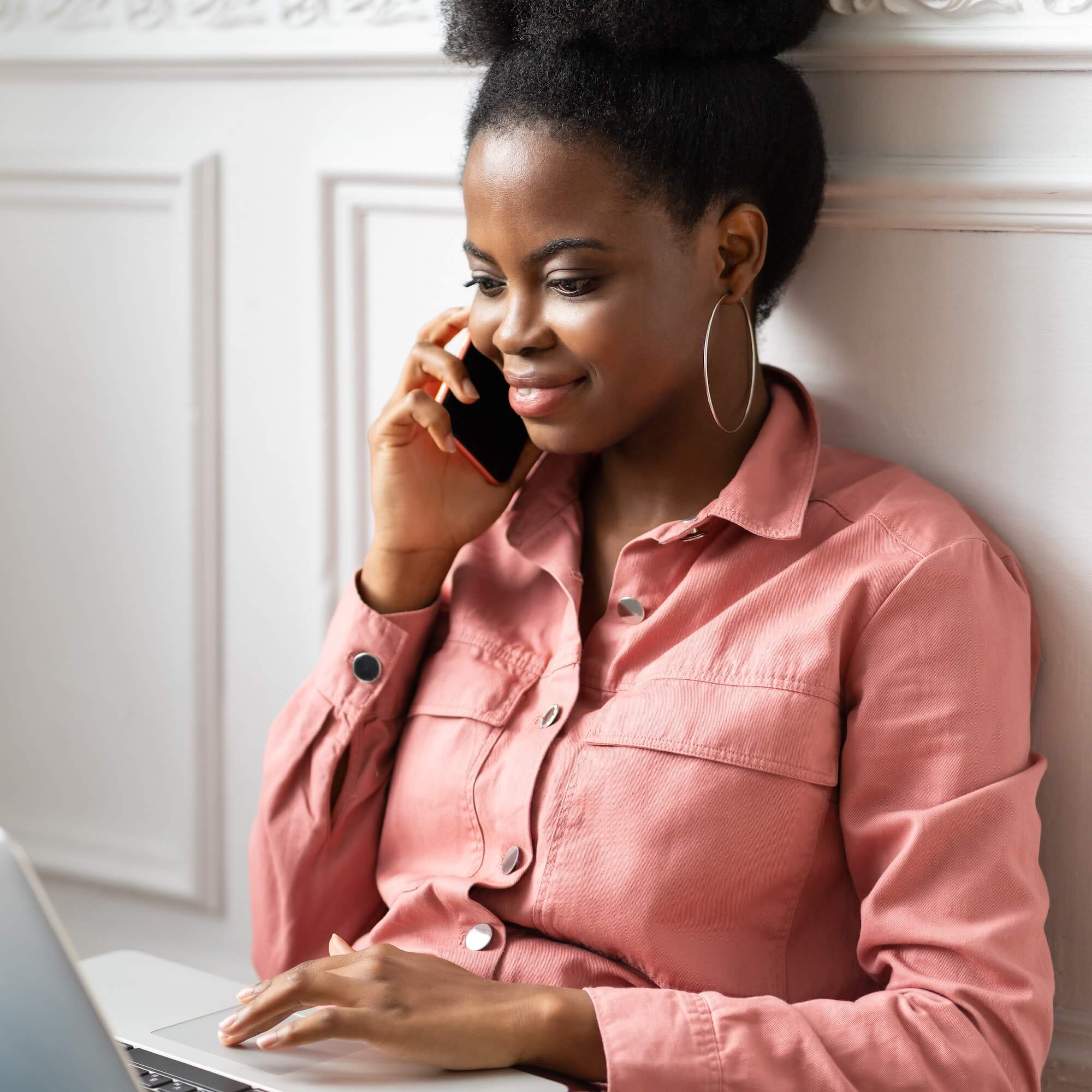 Focused african american millennial woman talking on phone remote working on laptop.jpg